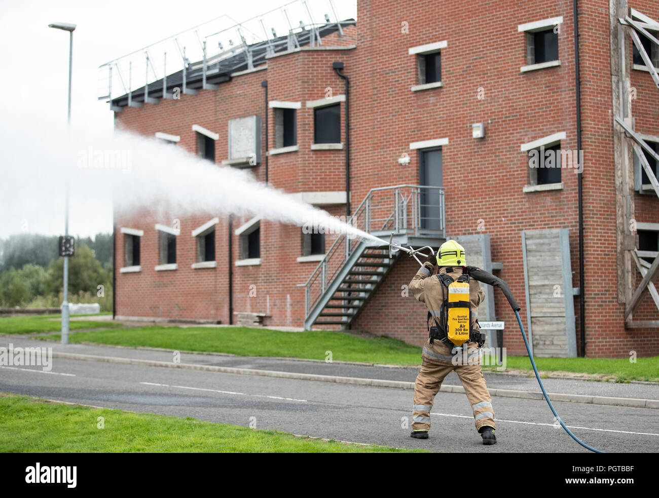 Feuerwehrleute des Scottish Fire and Rescue Service in ihrem National Training Center in Glasgow demonstrieren Ultrahochdrucklanzen, die unter dem Namen "Coldcut Cobra" firmiert und es Feuerwehrleuten ermöglichen, ein Feuerschutzmittel durch die Wand eines brennenden Gebäudes zu sprengen. Stockfoto