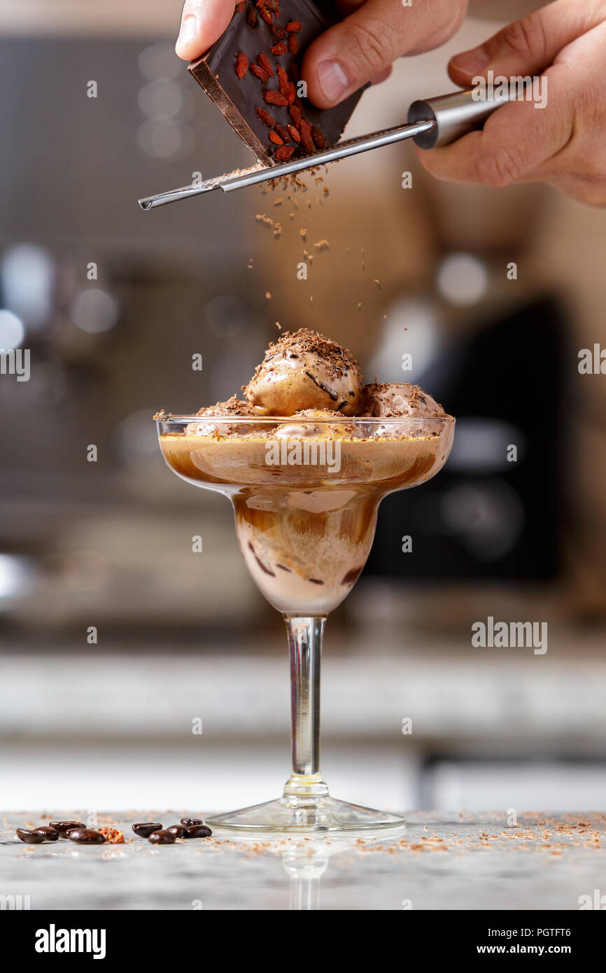 Die Hand des Mannes reiben Schokolade auf dem Affogato, espresso Eis Dessert im Glas Stockfoto