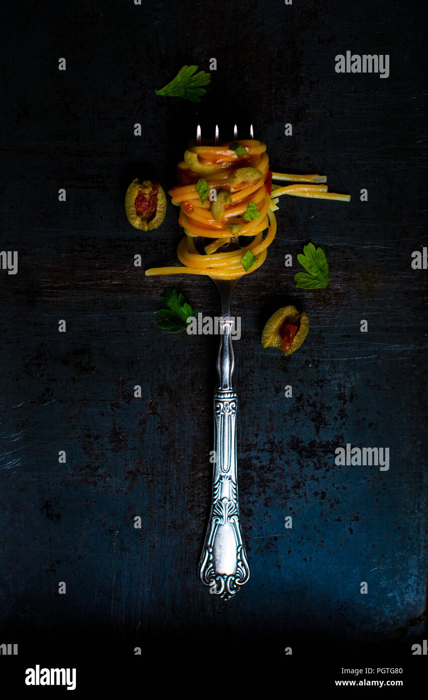Spaghetti Pasta mit Oliven und Petersilie aufgewickelt auf einer Gabel. Köstliche italienische Speisen. Stockfoto