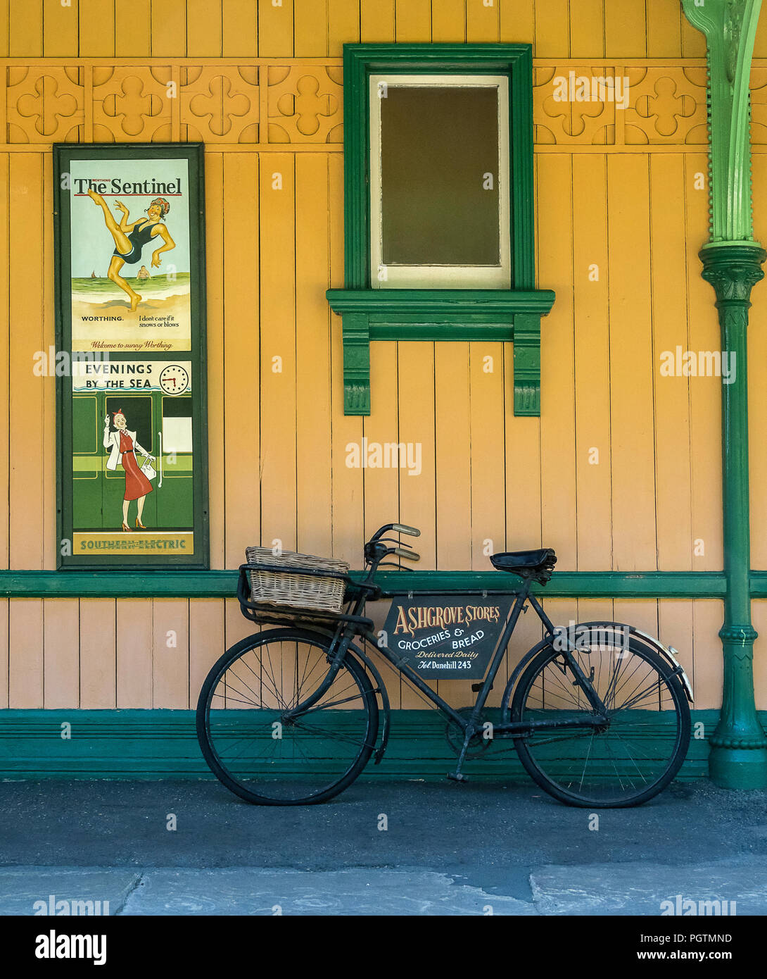 Grüne Fahrrad mit Werbung panel lehnte sich gegen eine Wand auf einer Plattform an Horsted Keynes Heritage Railway Station, East Sussex, England Stockfoto