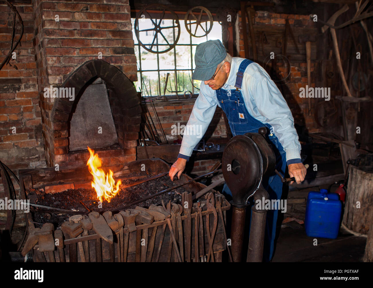 Ein Schmied pumpt Luft zu seinen Ofen in der Reproduktion vintage Workshop der Historischen Gesellschaft in Peacham, Vermont, United States gefördert. Stockfoto