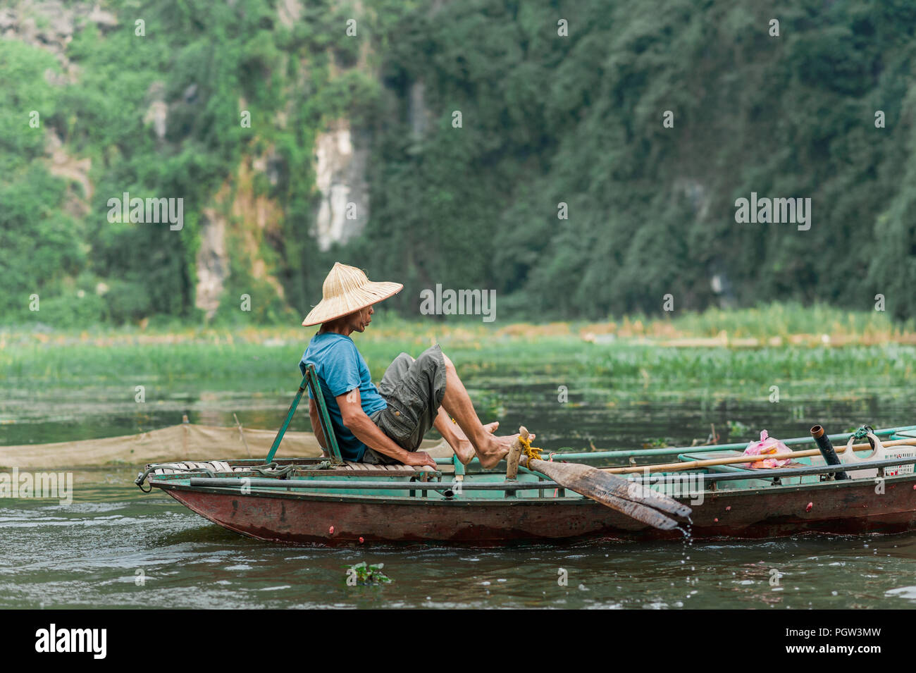 Lokale Mann in einem Reis hat Rudern mit dem Boot entfernt von Vung Straßenbahn Pier. Traditionelle Paddle - Bootsfahrt können die Touristen die Ngo Dong Fluss zu schätzen wissen. Stockfoto