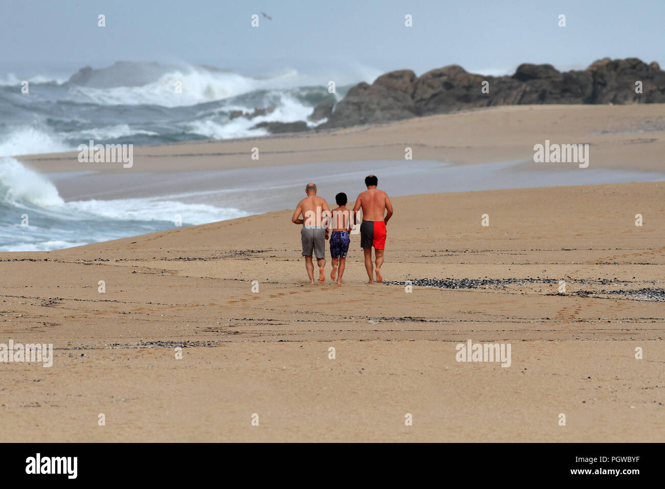 Matosinhos, Portugal - Oktober 19, 2014: Drei männliche Personen, zwei Erwachsene und ein junger Mann, der auf einem einsamen Strand im Norden Portugals Stockfoto