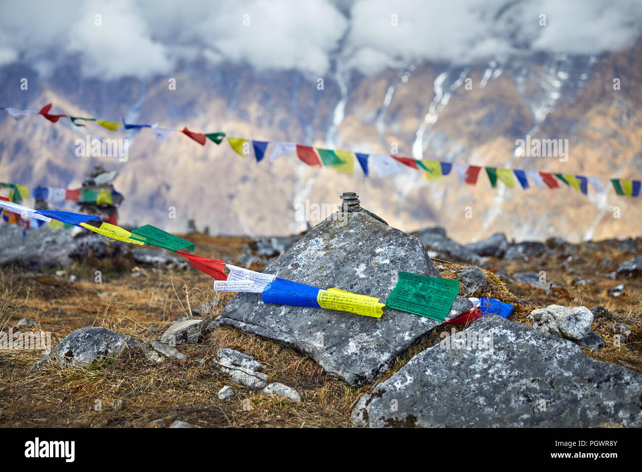 Kleine Haufen von Steinen und tibetischen Gebetsfahnen Lunge Ta am Mardi Himal Base Camp bei bewölktem Gipfeln des Himalaya in Nepal Stockfoto