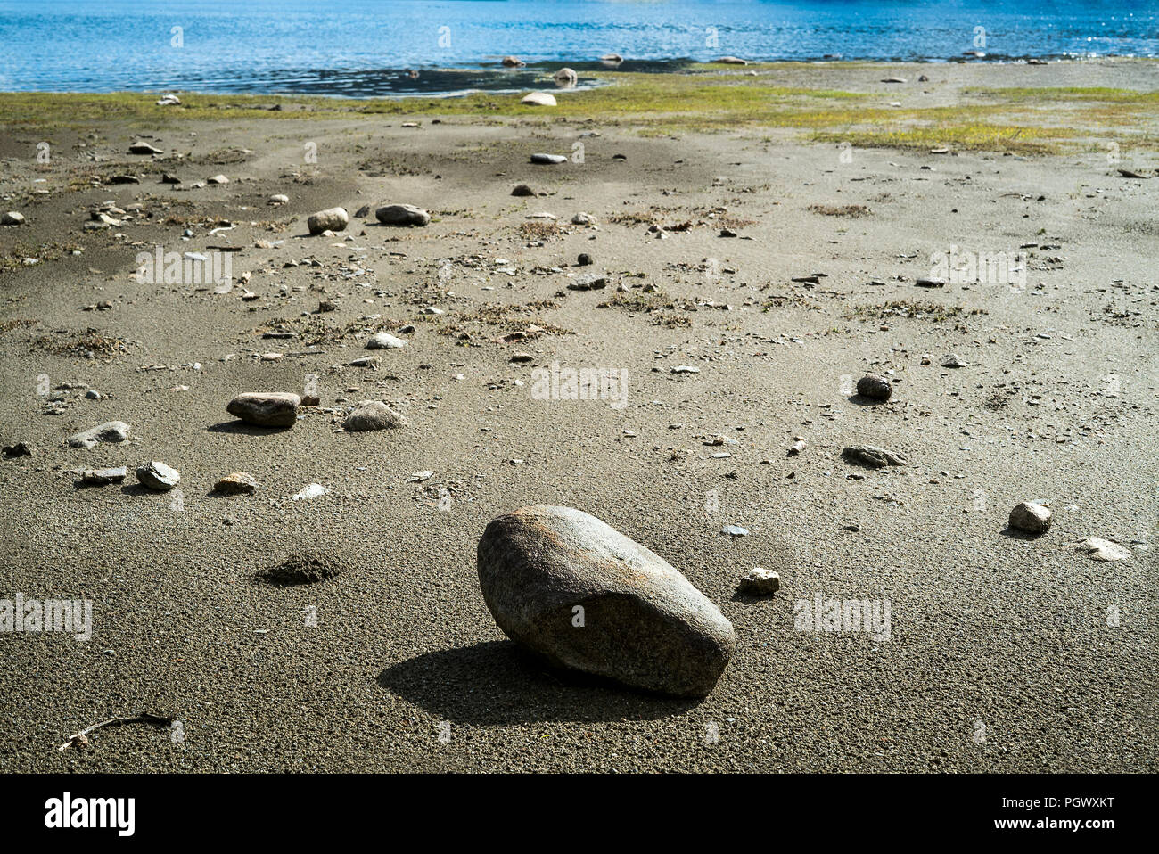 Sonnigen Küste Landschaft mit einer Vielzahl von kleinen Steinen und natürliche Textur auf der Oberfläche von Ebbe Sand Stockfoto