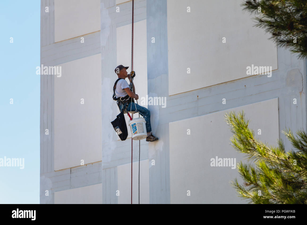 Sesimbra, Portugal - August 8, 2018: die Maler Kommen hinunter die Fassade eines Gebäudes Abseilen mit einem Seil Stockfoto