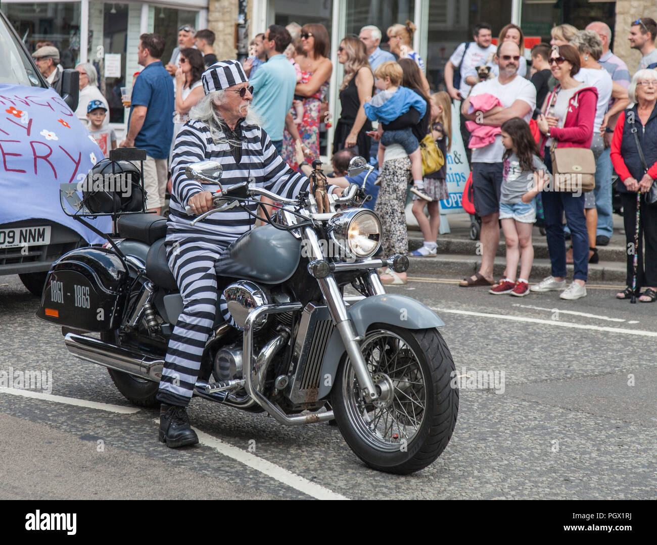Ein älterer Mann in einem Hooped jumpsuit und Reiten ein Motorrad bei der jährlichen Street Parade am Barnard Castle Treffen in Barnard Castle, England, Großbritannien Stockfoto