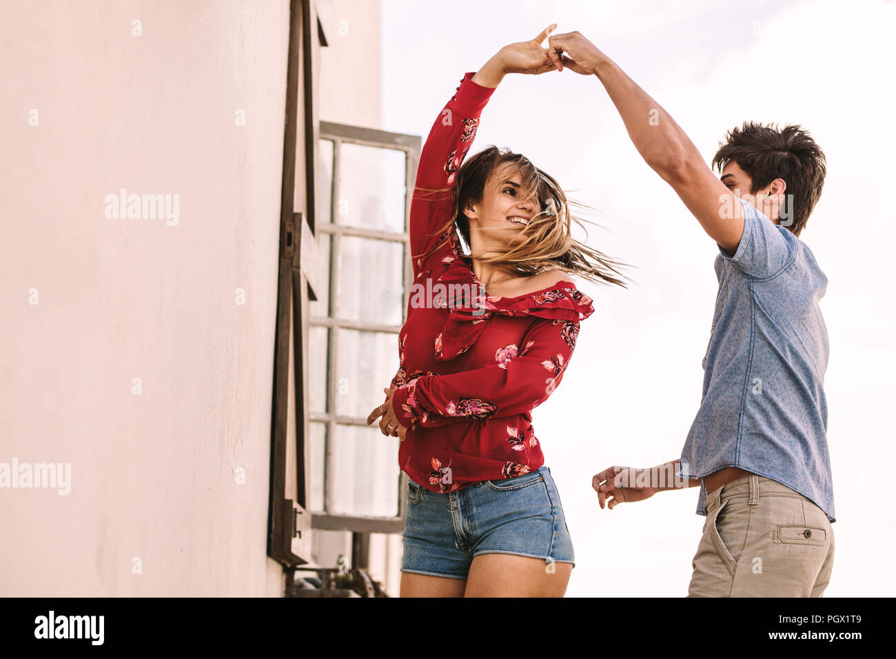 Lächelnd Mann und Frau tanzen. Mann seine Freundin halten ihre Hand über ihren Kopf beim Tanzen. Stockfoto