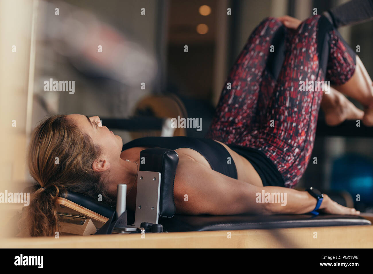Fitness Frau tun Pilates Workout liegen auf einem Gerät. Pilates Frau an einem Gym Übungen. Stockfoto