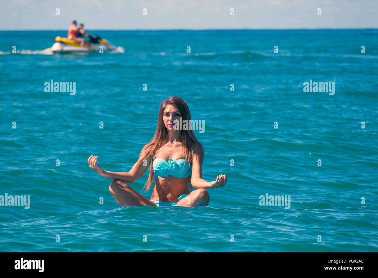 Frau entspannend auf einem SUP Verpflegung im Meer in einem Lotus darstellen. Paddle Board Yoga. Gesunder Lebensstil in Harmonie mit der Natur. Stockfoto