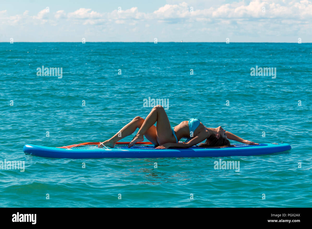 Frau entspannend auf einem SUP Verpflegung im Meer. Paddle Board Yoga. Gesunder Lebensstil in Harmonie mit der Natur. Stockfoto