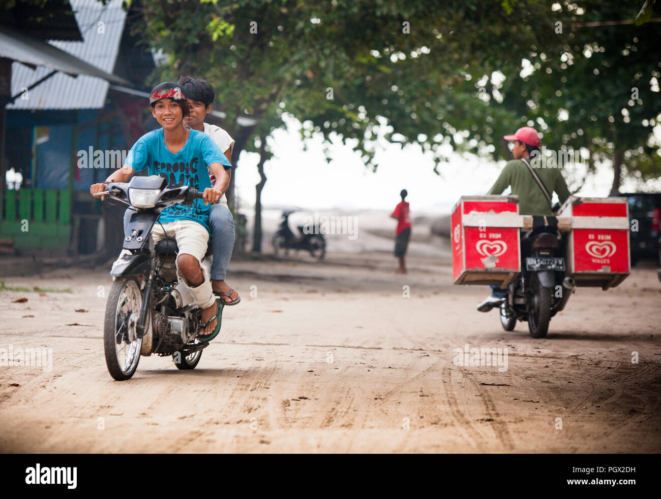 Eis Anbieter und einheimische Kinder auf Mopeds am Tanjung Tinggi, einen schönen Strand auf der Insel Belitung, berühmt durch hit Indonesische film Laskar Pelangi. Stockfoto