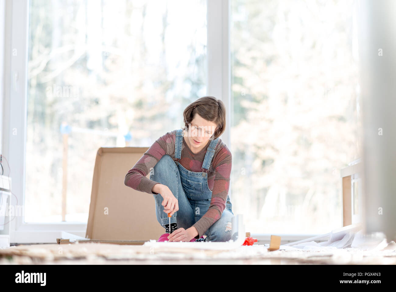 Junge Frau, DIY-Reparaturen zu Hause zusammenfügen Selbstmontage Möbel mit einem Schraubendreher. Stockfoto