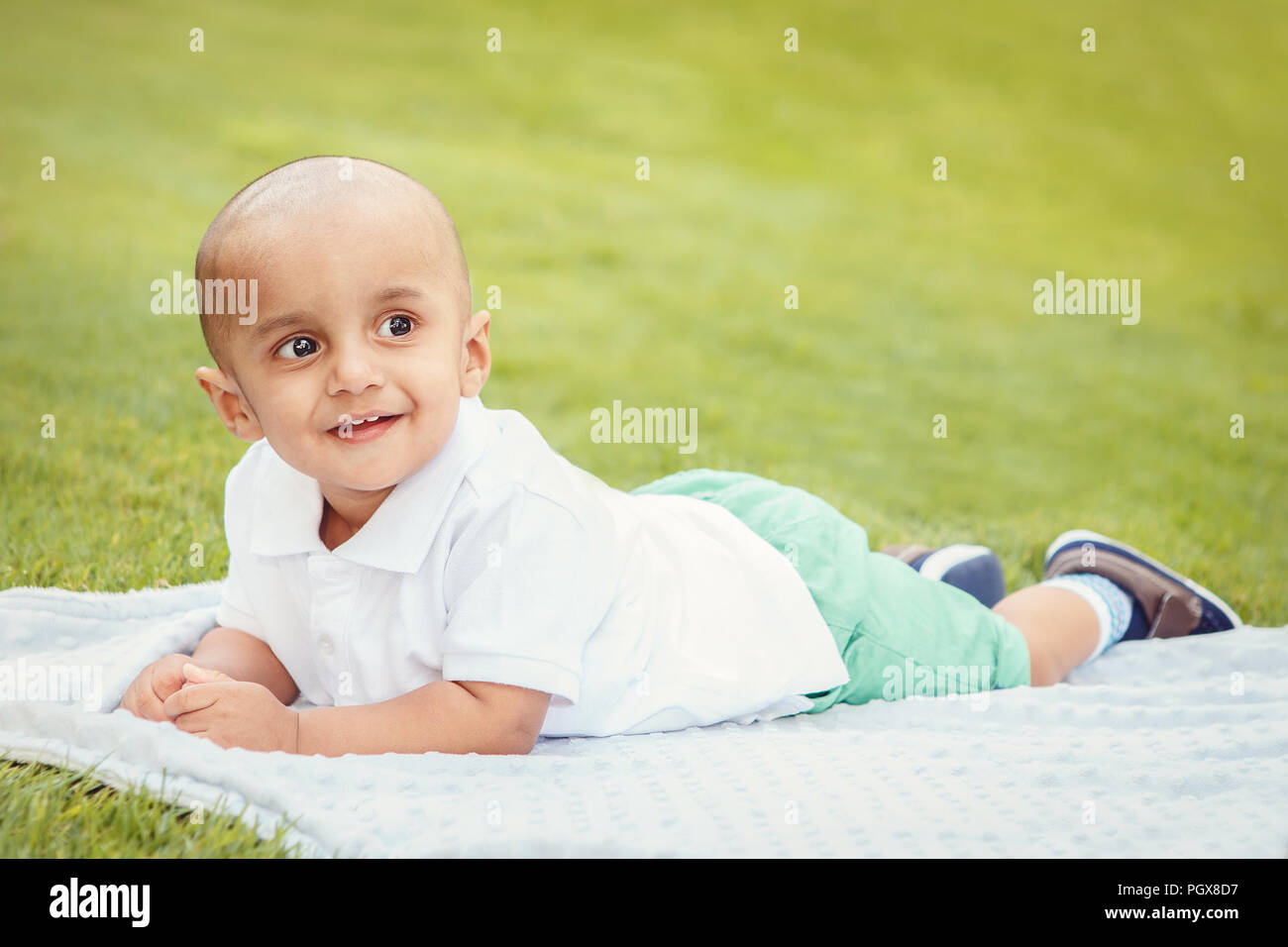 Portrait von cute adorable kleinen indischen Asiatischen oder Orientalischen baby boy im weißen Hemd Festlegung auf Erde in Park draußen auf hellen Sommertag Stockfoto