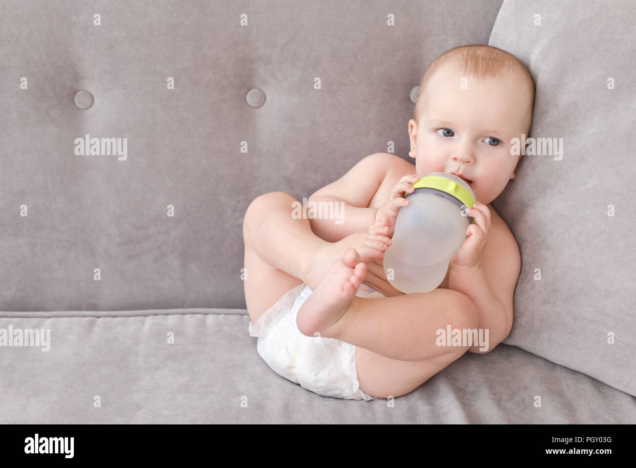 Fröhliches Baby mit Flasche auf dem Sofa Stockfoto