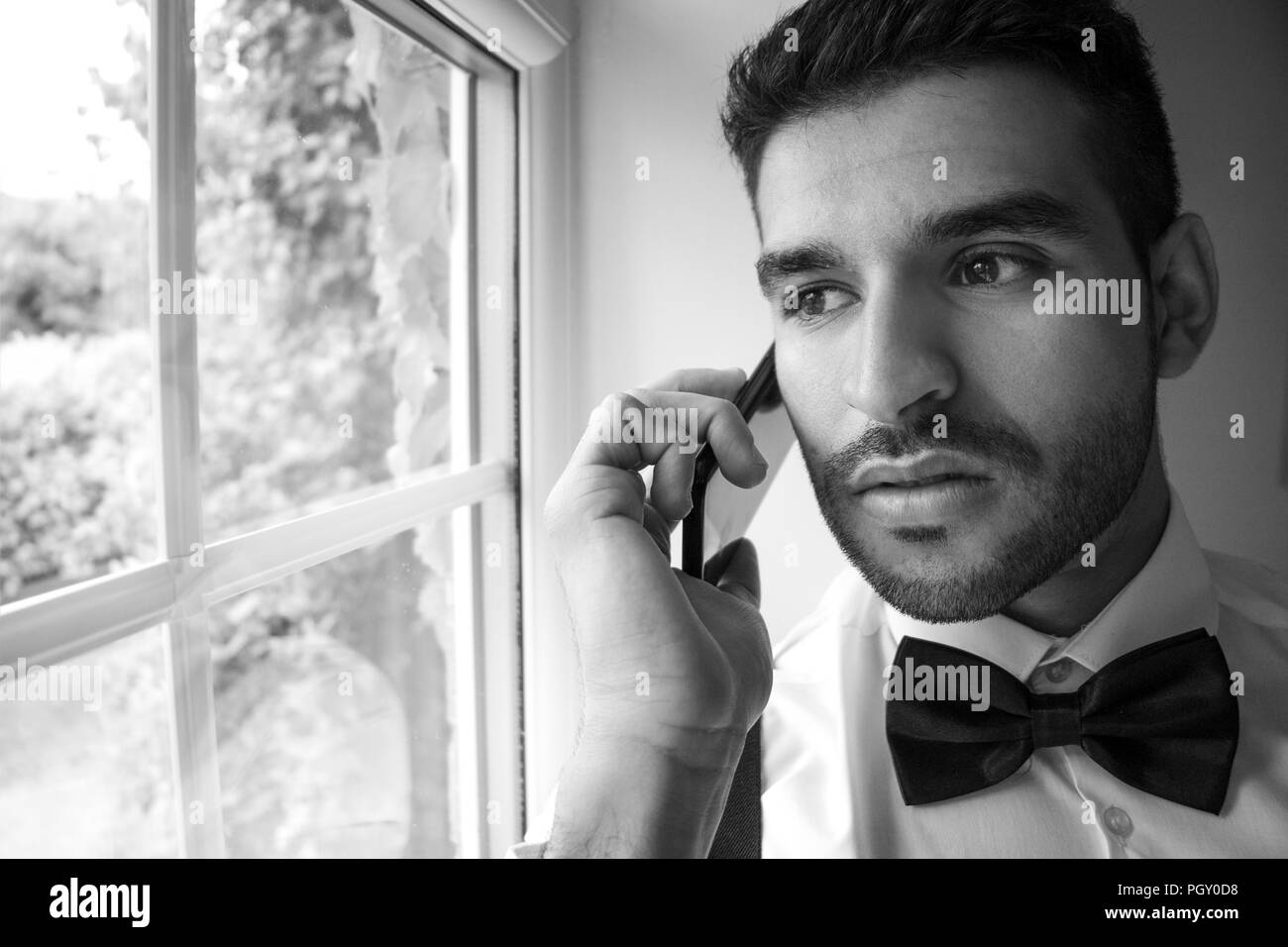 Professionelle business Mann im Smoking Gespräche am Mobiltelefon durch Fenster Stockfoto