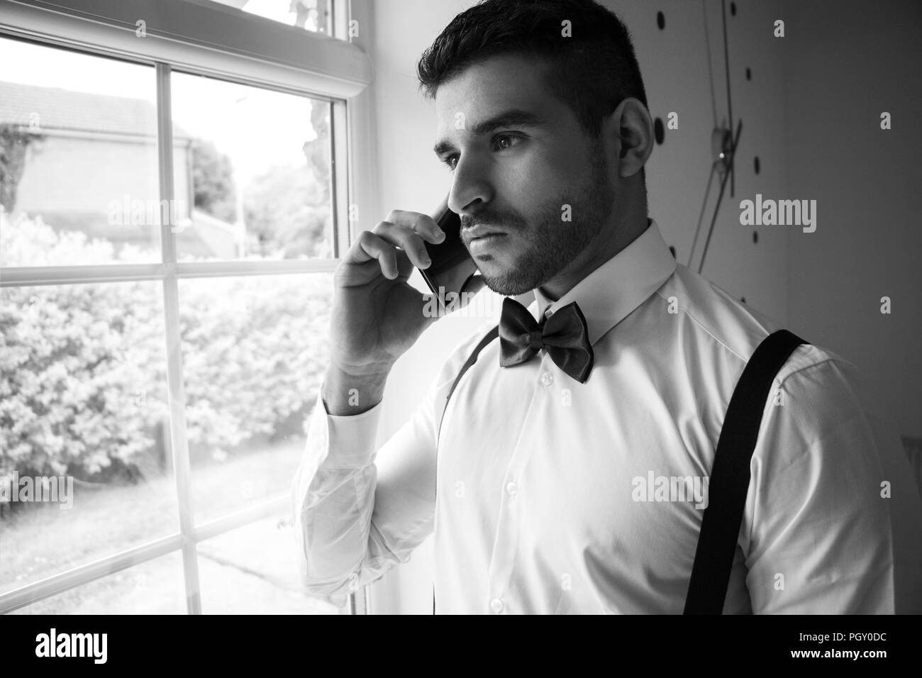 Professionelle business Mann im Smoking Gespräche am Mobiltelefon durch Fenster Stockfoto