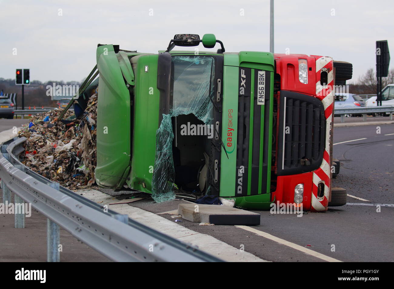 Ein Lkw umkippt und Leckagen ist es Laden der Verwertung von Abfällen über die neue Fahrbahn der Großen Yorkshire in Doncaster, South Yorkshire Stockfoto