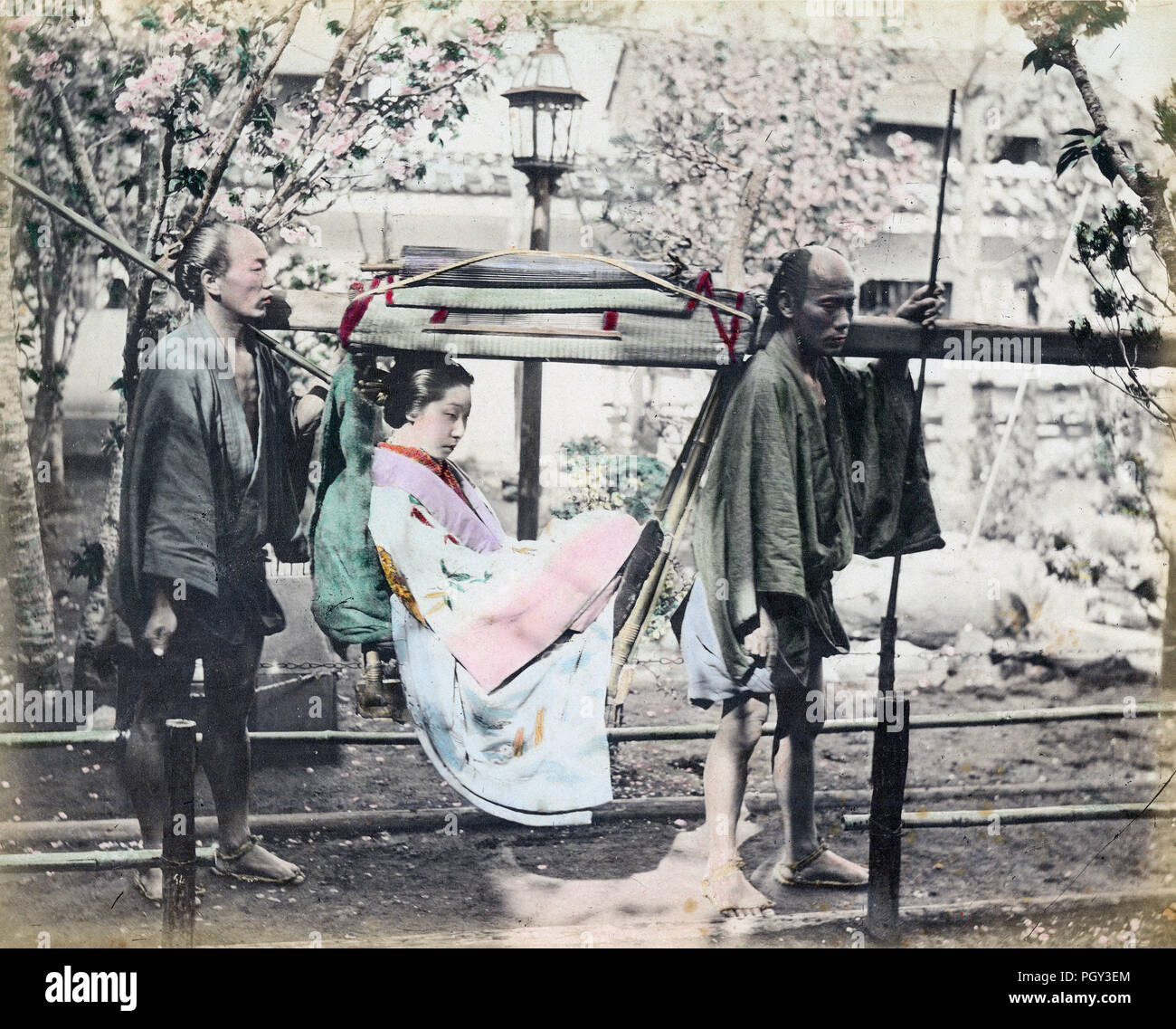 [1880s Japan - die Frau, die in einer japanischen Kago Sänfte]-Gruppe Porträt eines eleganten japanischen Frau in einem kago (Sänfte) durch zwei Träger durchgeführt. Die Träger haben die traditionellen Frisuren und Kleidung und halten den Atem ikizue (Sticks) ihre Atmung zu regulieren. Sie tragen Stroh Sandalen. Ein Regenschirm ist auf dem Dach platziert. Dies war die gemeinsame Ort Gepäck der Passagiere zu setzen. 19 Vintage albumen Foto. Stockfoto