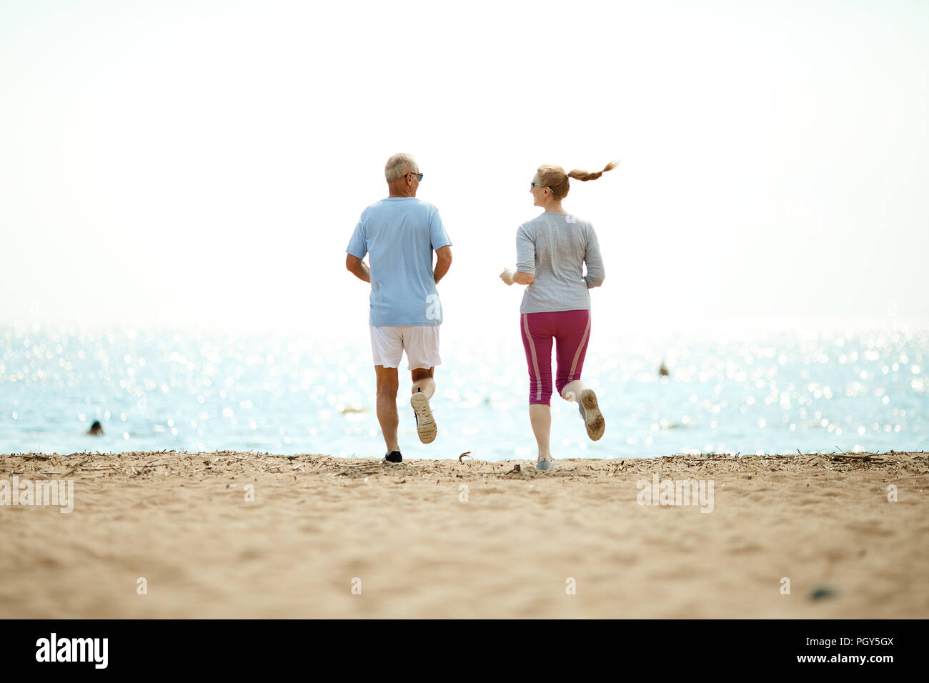 Happy energetische im Alter von Paar in Activewear in Richtung Wasserseite beim Training am Strand Stockfoto