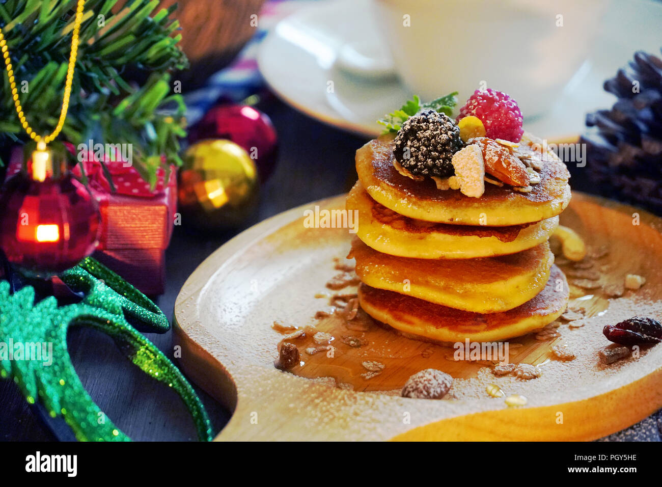 Pfannkuchen mit Beeren und Mutter mit Hintergrund Geschenk und Pine Cone unter Weihnachtsbaum, Holiday Party Dessert. Stockfoto