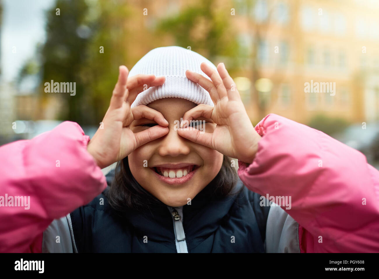 Fröhliches Mädchen mit toothy Lächeln halten ihre Finger zusammen mit den Augen Stockfoto