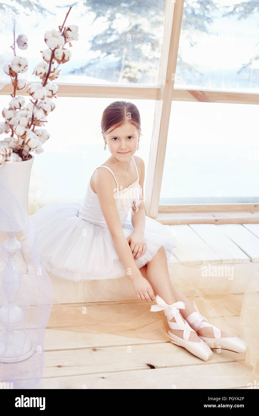 Junge ballerina Mädchen ist die Vorbereitung für eine Ballettaufführung.  Kleine prima Ballett. Mädchen in einem weißen Ballkleid und Pointe in der  Nähe der Fenster, schöne rote h Stockfotografie - Alamy