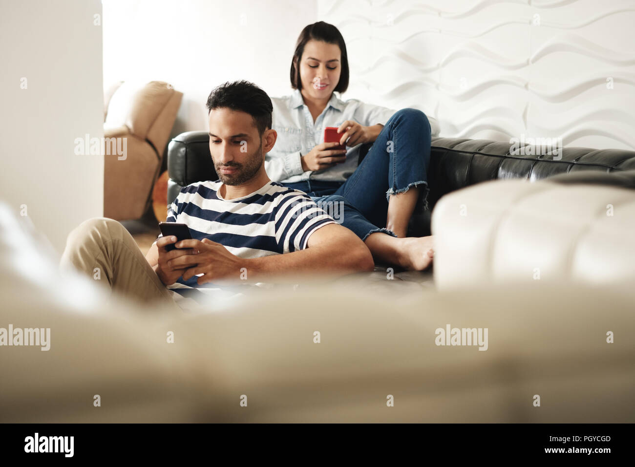 Happy Hispanic Paar mit Smartphones auf der Couch zu Hause Stockfoto