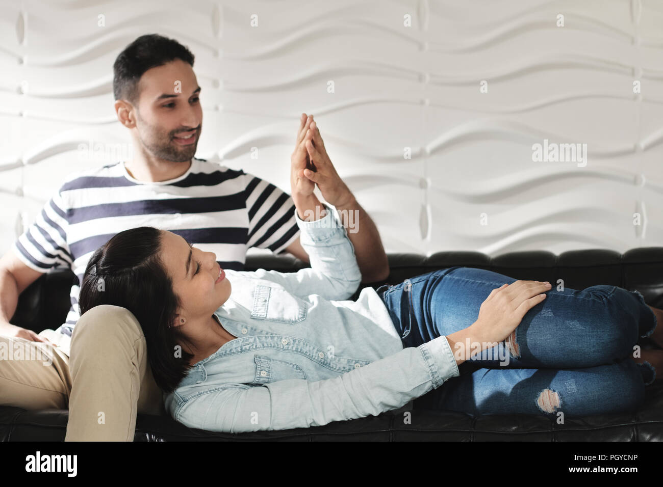 Gerne Latino Paar Hände halten und lächelnd auf dem Sofa Stockfoto