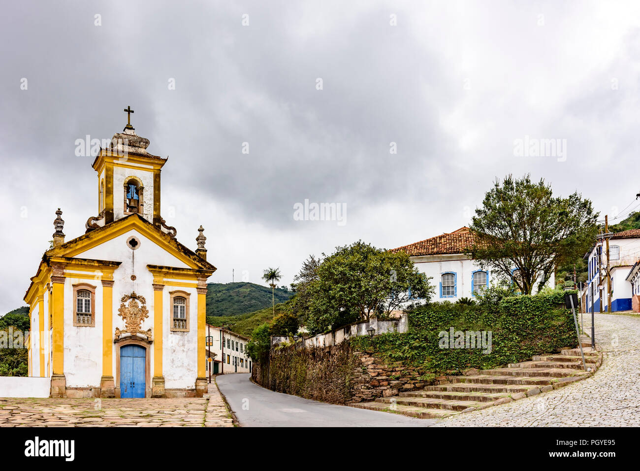 Alte historische Kirche, houases und Strassen in der brasilianischen Stadt Ouro Preto mit dunklen Wolken im Hintergrund Stockfoto