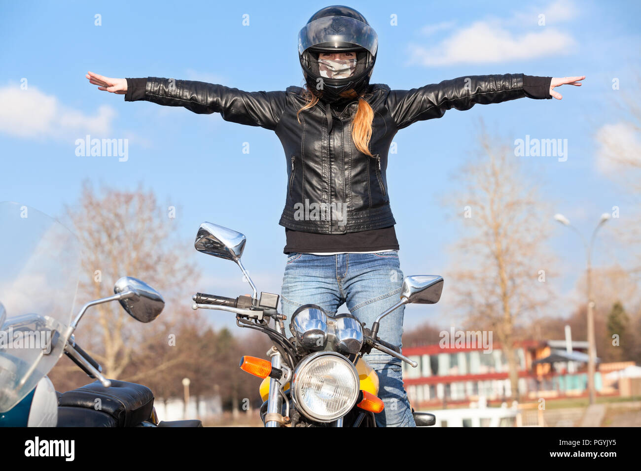 Stunt Mädchen Balancing während Fahrten Motorrad ohne Hände, Arme seitlich verlängert Stockfoto