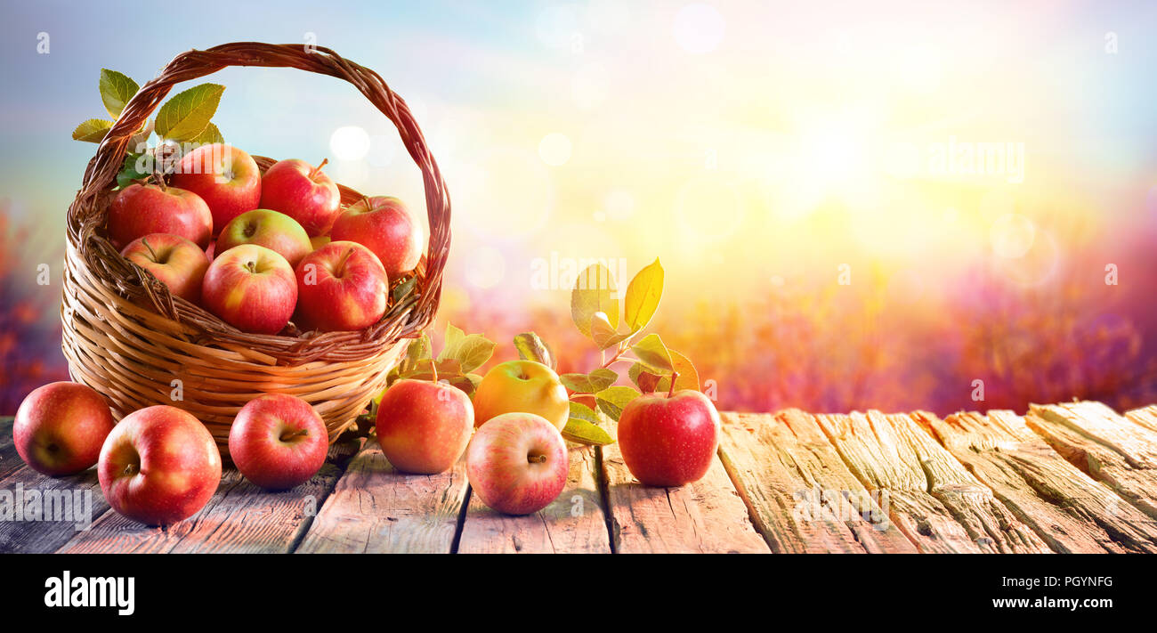 Rote Äpfel im Korb im Alter von Tabelle bei Sonnenuntergang Stockfoto