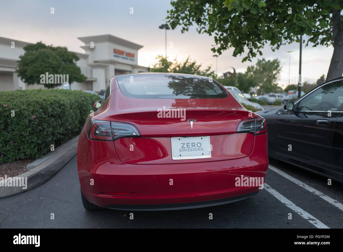 Rückansicht eines roten Tesla Modell 3 Elektroauto von Tesla Motors mit einem Nummernschild Null Emissionen Lesung im Rahmen einer dramatischen Himmel in der San Francisco Bay Area, Dublin, Kalifornien, 21. Mai 2018. () Stockfoto