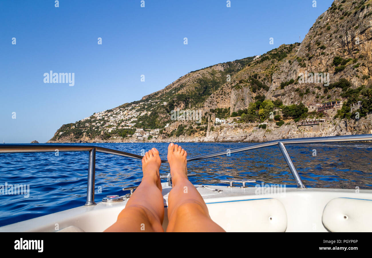 Gebräunte Beine auf dem Boot auf Amalfiküste in Italien Stockfoto
