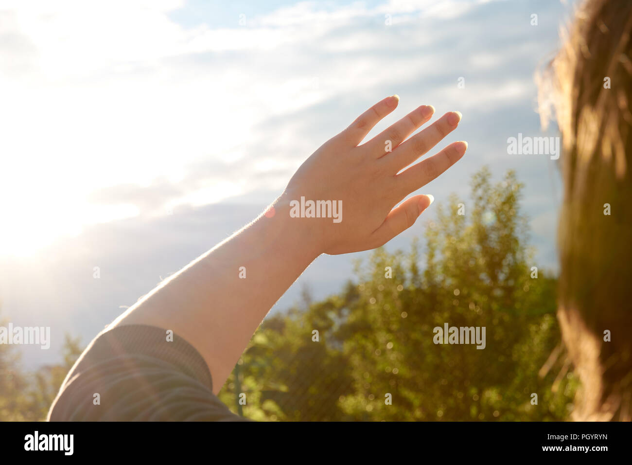 Eine junge Frau schützt Ihre Augen und Ihre Haut vor der Sonne mit ihren Händen. Sonnenlicht, Outdoor. Stockfoto