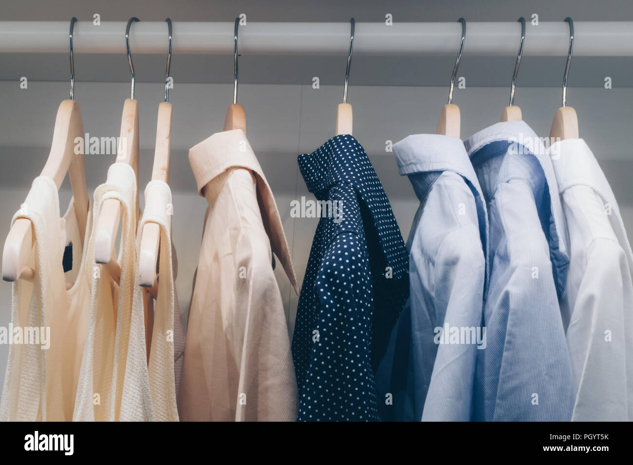 Bekleidung Männer Shirt und weibliche Kleid hängen auf dem Schrank in der Familie Ankleidezimmer zu Hause. Cool Tone und Film style Foto. Stockfoto