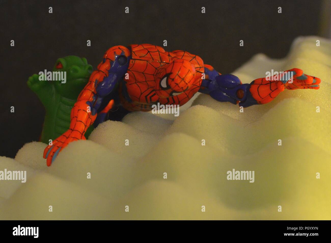 Slinkachu Style Setting: Spider-Man Klettern ein Hügel mit seinen kleinen grünen Freund Stockfoto