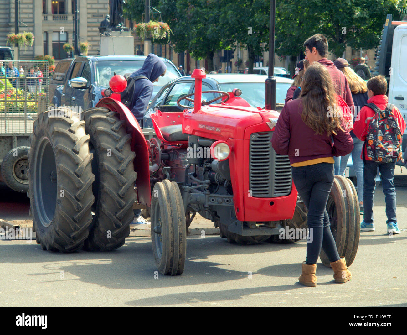 Glasgow, Schottland, Großbritannien. 29 August, 2018. Mittags Besucher, wo man ein bisschen lebendiger Geschichte als Classic Red 1964 Massey Ferguson 35 X Traktor behandelt erschien in der Stadt George Square. Einheimische und Touristen beobachtet, wie der Rasen, die für die jüngsten europäischen Meisterschaften einladenden Zentrum aufgehoben wurde ersetzt wurde. Das Modell Sport ungewöhnliche Doppel Räder die Traktion zu erhöhen und wurde von der stolze Besitzer dargestellt geändert. Gerard Fähre / alamy Nachrichten Stockfoto