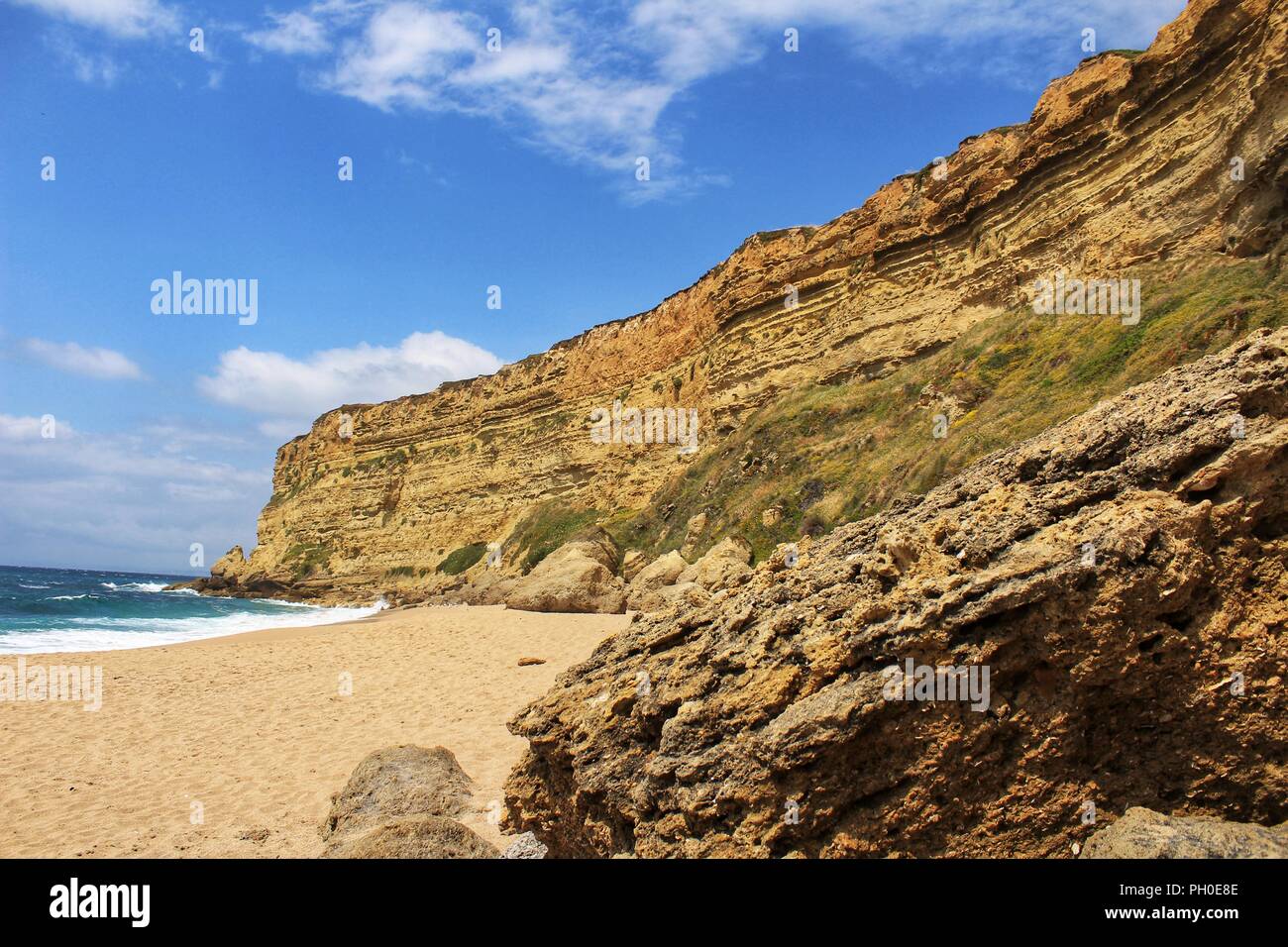 Crystal Clear und wilde Gewässer in Praia da Foz, Sesimbra, Portugal. Golden Sand, Möwen fliegen, Klippen und Felsen Stockfoto