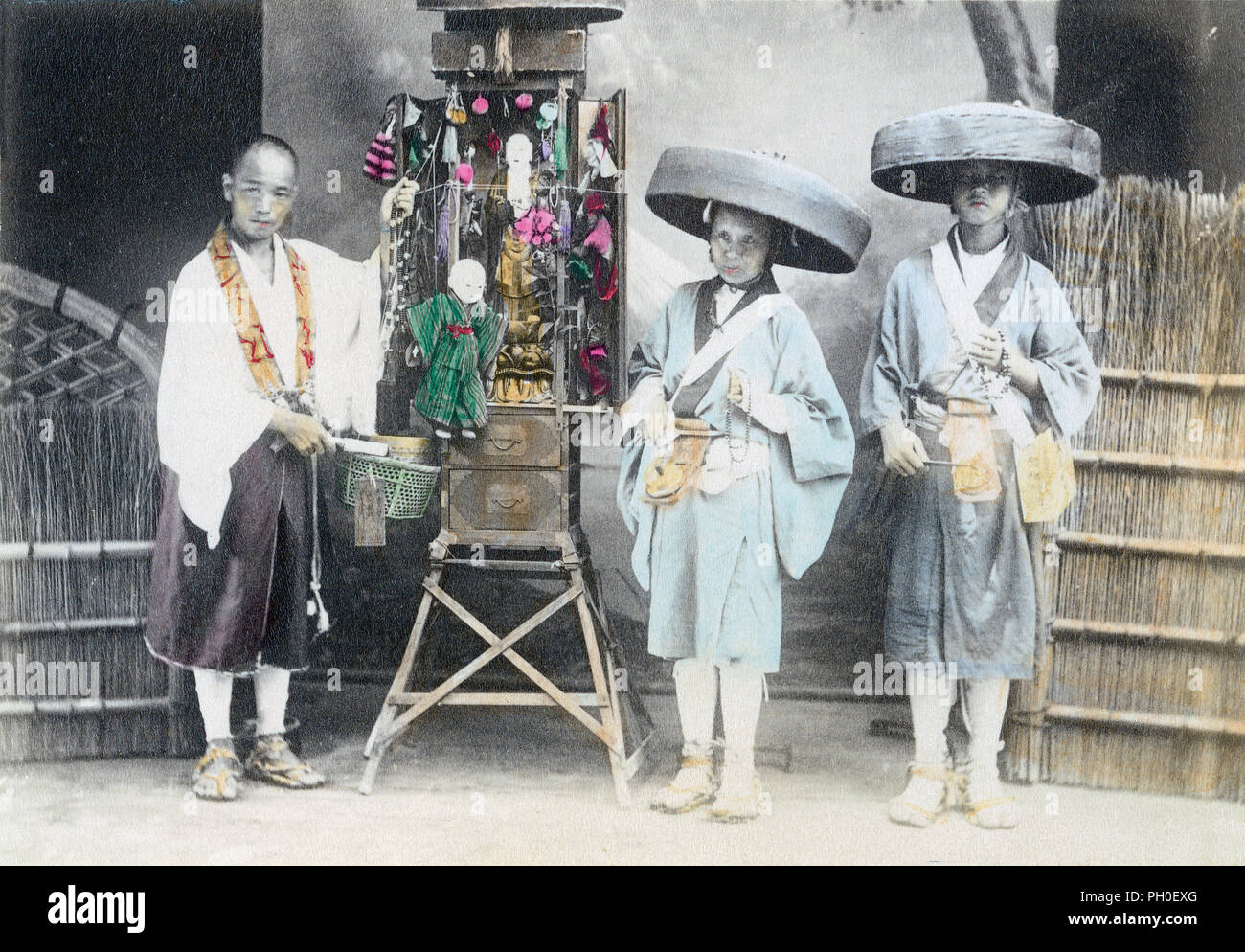 [1890s Japan - Pilger mit einem tragbaren buddhistische Heiligtum] - Drei Pilger mit einem tragbaren buddhistische Heiligtum. Die beiden Menschen auf der rechten Seite tragen Kaki (Bambus Hüte) sind Pilger Bettler bekannt als Hachitataki. Sie würden von Haus zu Haus, am vorderen Eingang und Gesang stehen, während die Glocken läuten hängen von ihren Gürtel. Das ursprüngliche Bild ist klein, so dieses Bild sich nicht gut für sehr große Verwendungen zu verleihen. 19 Vintage albumen Foto. Stockfoto