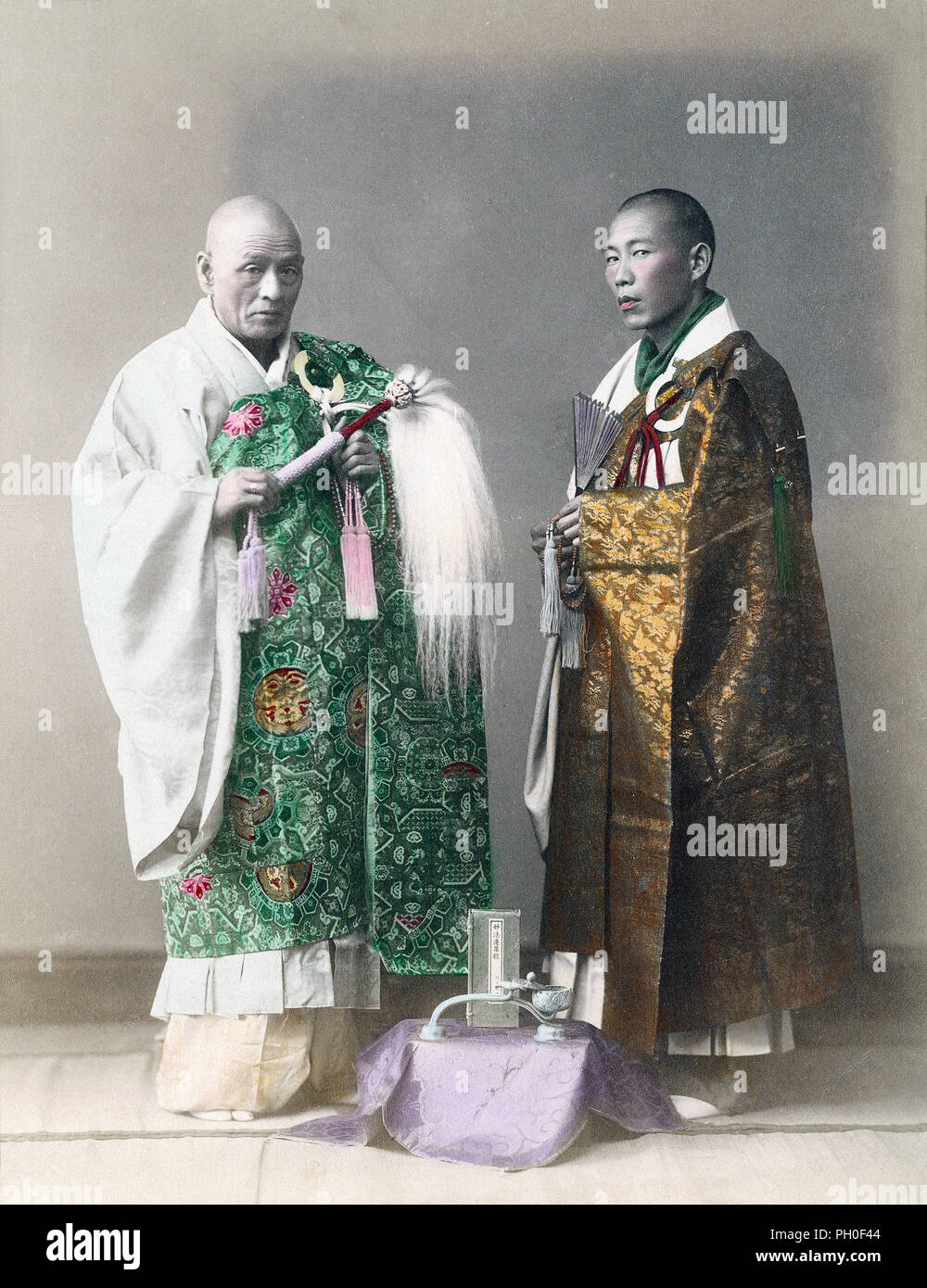 [ 1890er Japan - zwei buddhistische Priester ] - EIN Studiobild von zwei buddhistischen Priestern. Der Priester auf der linken Seite hält Juzu Gebetsperlen und einen Hossu (払子) Staf mit gebündeltem Haar. Der andere trägt auch Juzu und einen Fan. Beide tragen eine Mönchsstola, genannt Kesa, aus üppigem Seidenbrokat. Vintage Albumin Foto des 19. Jahrhunderts. Stockfoto