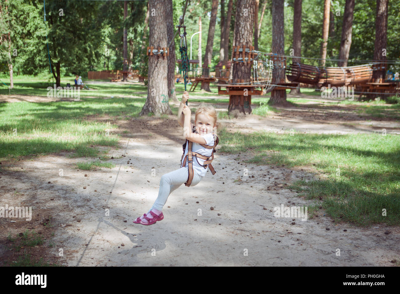 Freizeitaktivität. Kleines Mädchen auf einem Karabiner kreuze das Seil in einer extremen Seilpark. Stockfoto