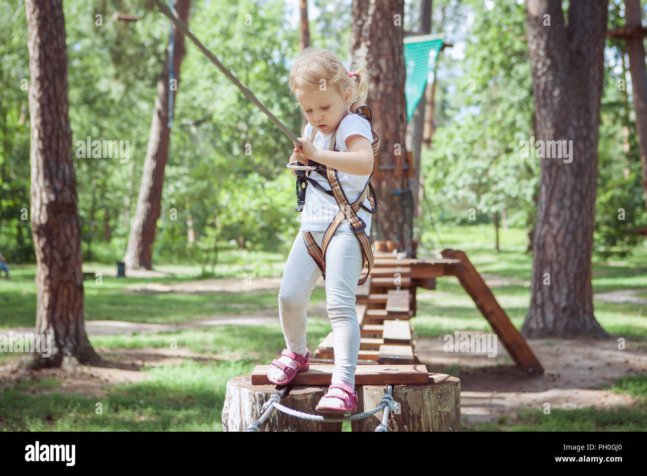 Freizeitgestaltung für Kinder. Kleines Mädchen Spaß im Seilpark. Stockfoto