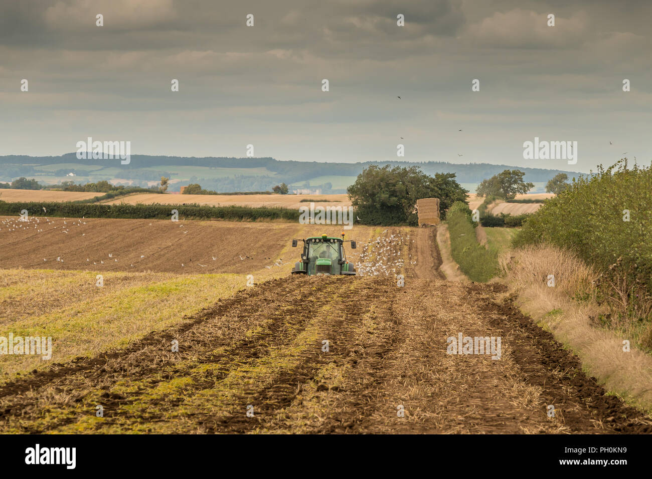 Großbritannien Landwirtschaft, einem John Deere Traktor über Sub soiler einem Abgeernteten Feld für die Aussaat mit Rammstein bereit zu pflegen folgende Stockfoto