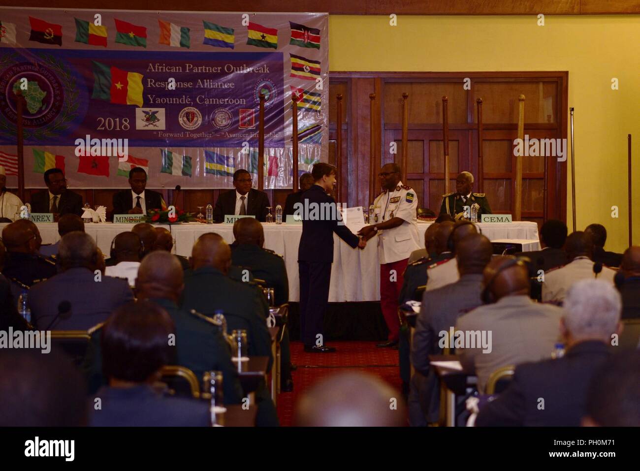 Us Air Force Colonel Krystal Murphy, US Africa Command Stellvertretender Befehl Chirurg, präsentiert Gabun Gen. Jean Raymond Nzenze APORA, Vorsitzender und Generaldirektor der militärische Gesundheitsdienst, die mit einem Buchstaben von US Marine Corps Gen. Thomas Waldhauser, AFRICOM Commander, während die afrikanischen Partner Ausbruch Response Alliance Eröffnungsfeier, Juni 18, 2018, Yaoundé, Kamerun. Verschiedene US-Agenturen zusammen mit 20 afrikanischen Partnerstaaten, zusammenarbeiten und Best Practices ausrichten Antwort Funktionen für Ausbrüche der auftretenden Infektionskrankheiten zu verbessern. Stockfoto