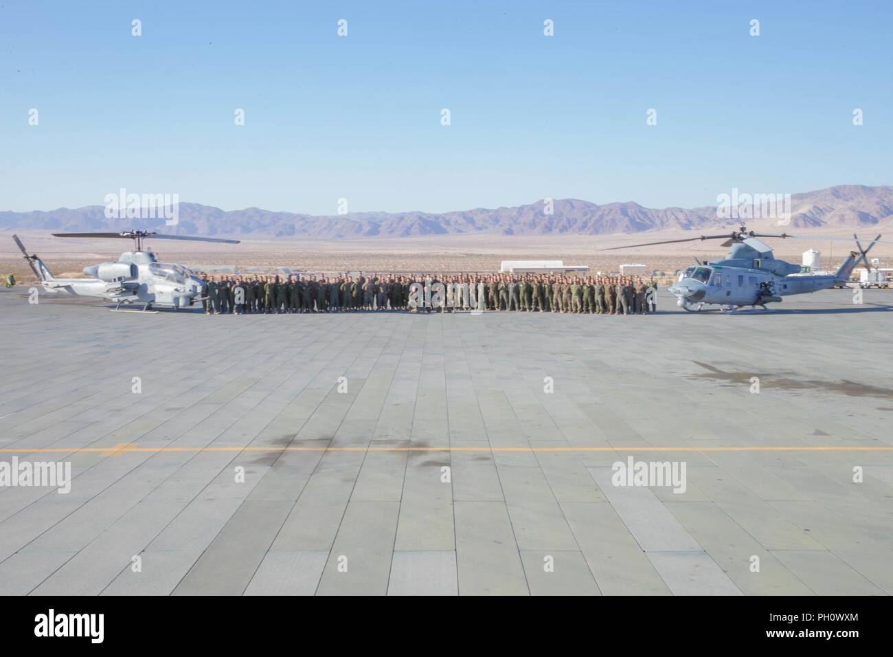 Marines mit Marine Leichter Hubschrauber Attack Squadron 775, Marine Flugzeuge Gruppe 41, 4 Marine Flugzeugflügel, für ein Gruppenfoto der nächsten AH-1W SuperCobra (links) und ein UH-1Y Venom (rechts), während integrierte Ausbildung Übung 4-18 bei Marine Corps Air Ground Combat Center Twentynine Palms, Calif., 21. Juni 2018 dar. HMLA-775, auch bekannt als "kojoten", vorausgesetzt Air Combat element Unterstützung für Marine Air Ground Task Force 23 während ITX 4-18. Stockfoto