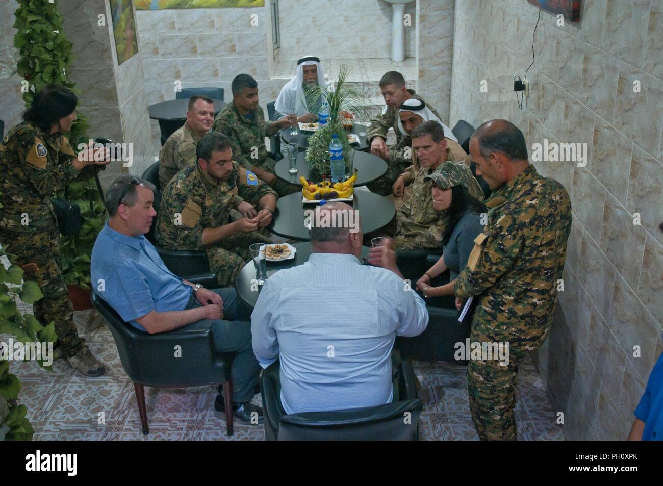 Us-Armee General Joseph Votel, Central Command Commander, John Rood, Staatssekretär der Verteidigung für Politik, Generalmajor Jaime Jarrard, Special Operations Joint Task Force - inhärenten Lösen Kommandeur, Generalleutnant Paul Funk, Combined Joint Task Force - inhärenten Lösen Kommandanten und Führungskräfte aus der Syrischen demokratischen Kräfte sprechen mit einem Geschäft Inhaber in Manbij, Syrien, 21. Juni 2018. Dieses Projekt war Teil einer Tour durch die Stadt für die Führer, um zu sehen, wie sicher und Wohlstand hat die Stadt geworden, seit die SDF-ISIS aus dem Bereich beseitigt. Stockfoto