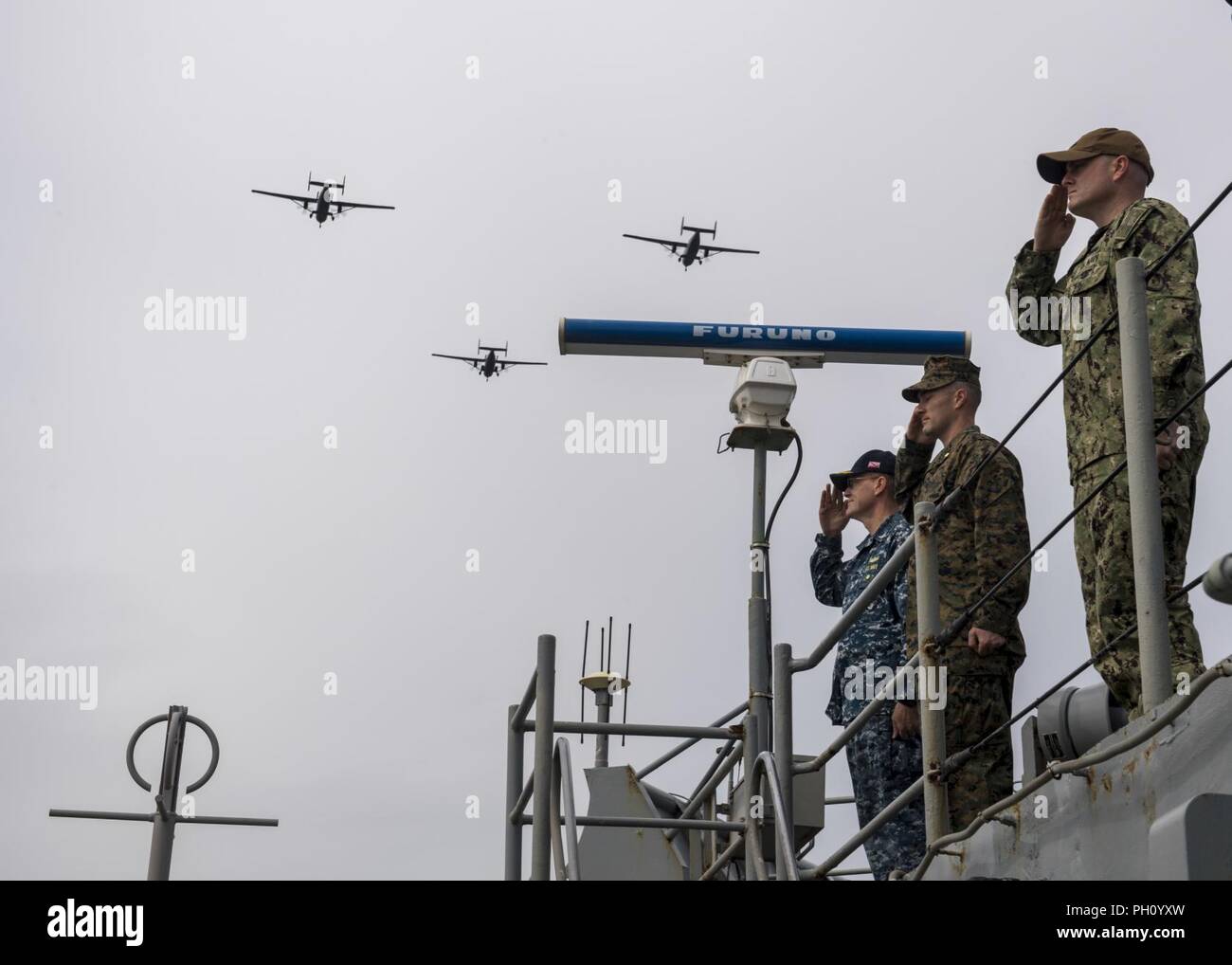 Polen (24. Juni 2018) Kapitän Brian J. Finman, Deputy Commodore von Amphibischen Squadron 4, links, US Marine Maj. Joseph Murphy, 26 Marine Expeditionary Unit, das Kommando über Truppen, Mitte, und Leutnant Kenneth Duley render Ehren als Polnische Flugzeuge fliegen über die Harpers Ferry-Klasse dock Landung Schiff USS Oak Hill (LSD 51) während einer Parade von Schiffen zu Ehren von Polen 100-Jahr Jubiläum der Marine, in Gdynia, Polen, 24. Juni 2018. Oak Hill, homeported in Virginia Beach, Virginia, ist die Durchführung von naval Operations in den USA 6 Flotte Bereich der Operationen. Stockfoto