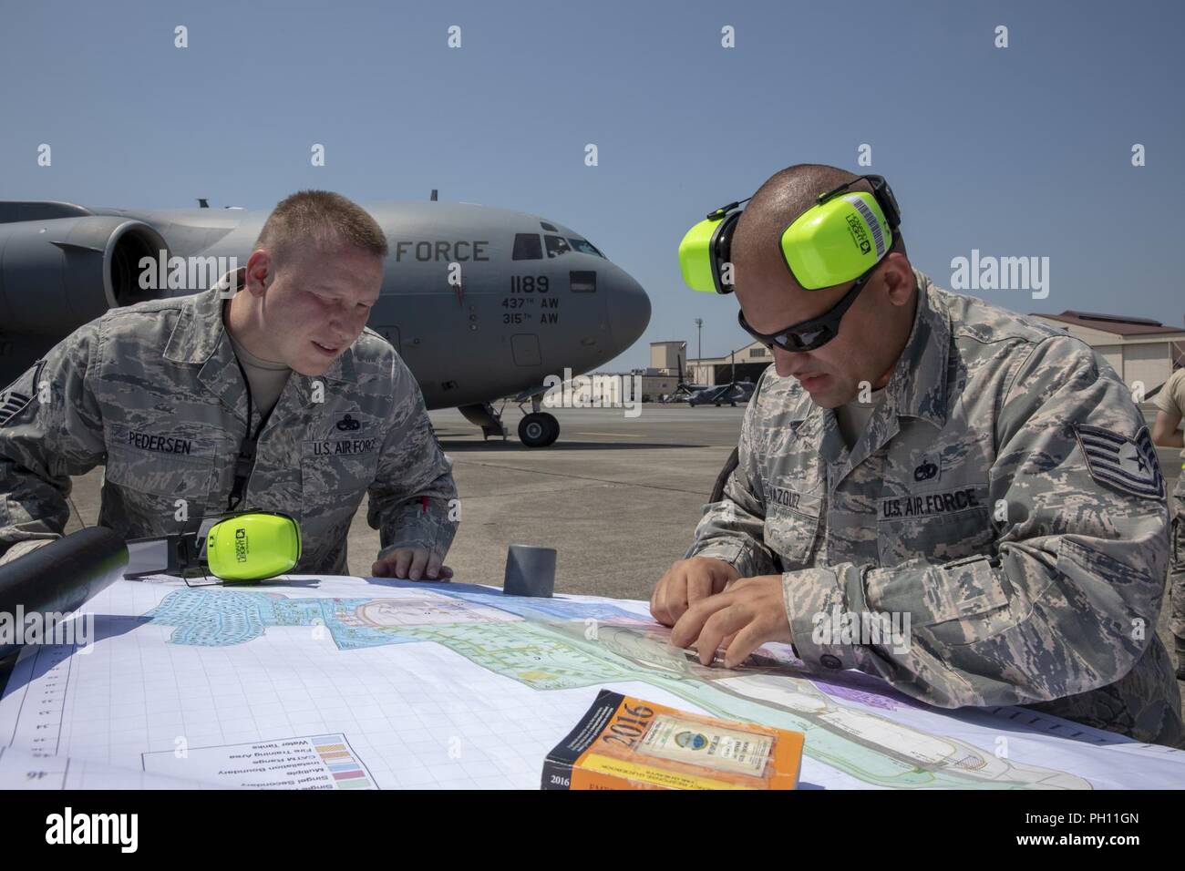 (Rechts nach links) Tech. Sgt. Brandon Vasquez und Master Sgt. Lee Pedersen, beide 730th Air Mobility Squadron Crew Chief, Plot, der Cordon während ein Notfallplan Übung in Yokota Air Base, Japan, 25. Juni 2018. Flieger von der 730th Air Mobility Squadron und 374 Bauingenieur Squadron Feuerwehr führte eine simulierte Feuer an Bord einer C-17 und Einarbeitung Training. Stockfoto