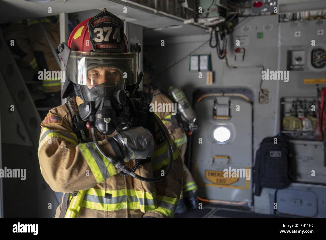 Junichiro Sugita, 374 Bauingenieur Squadron Feuerwehrmann, kommuniziert mit seinem Team während einer Notfallorganisation Übung in Yokota Air Base, Japan, 25. Juni 2018. Flieger von der 730th Air Mobility Squadron und 374 CES führte eine simulierte Feuer an Bord einer C-17 und Einarbeitung Training. Stockfoto